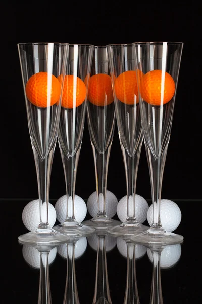 Cinque bicchieri di champagne, palline da golf bianche e arancioni — Foto Stock