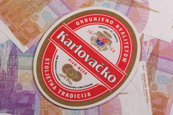 Beermat з Karlovacko пивом та Хорватії гроші. — стокове фото