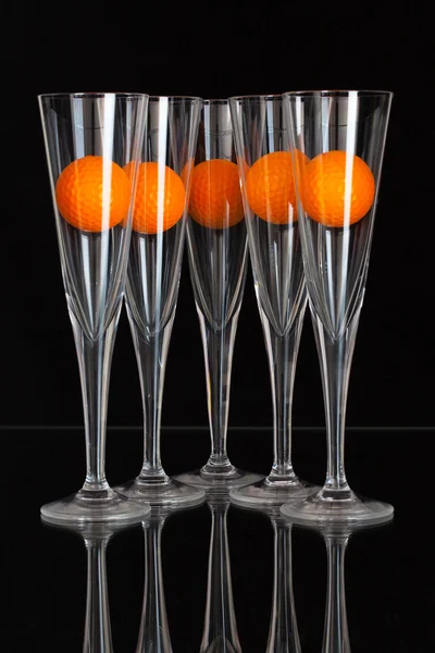 Cinque bicchieri di champagne e palline da golf arancioni — Foto Stock