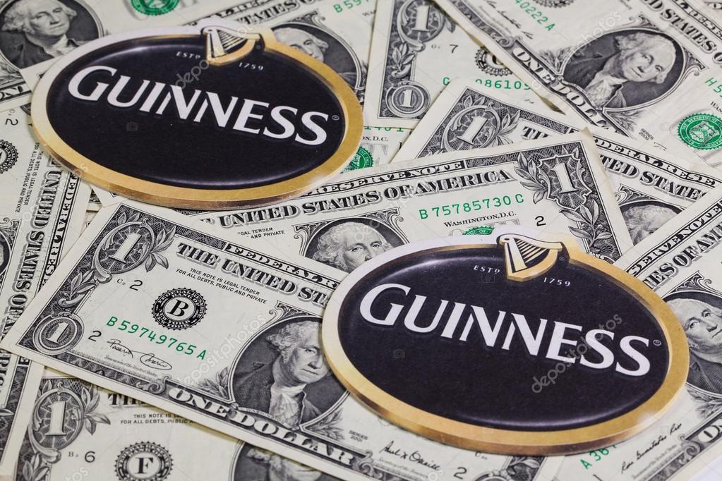 England,London - November 11, 2014:Beermats from Guinness beer and US dollars.Guinness is an Irish dry stout that originated in the brewery of Arthur Guinness at St. James  Gate, Dublin.