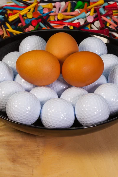 Golf balls and eggs on a black plate — Stock Photo, Image