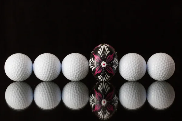 Golf balls and egg on a black glass table — Stock Photo, Image