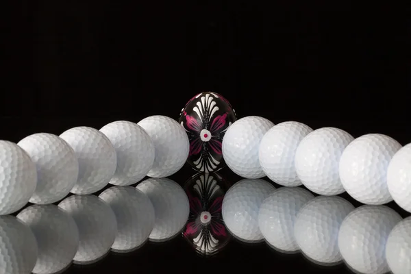 Bolas de golf y huevo en un escritorio de cristal negro —  Fotos de Stock