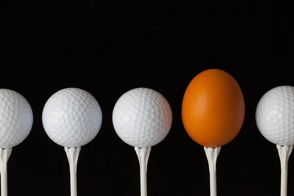 Bolas de golfe e ovo em uma mesa de vidro preto — Fotografia de Stock