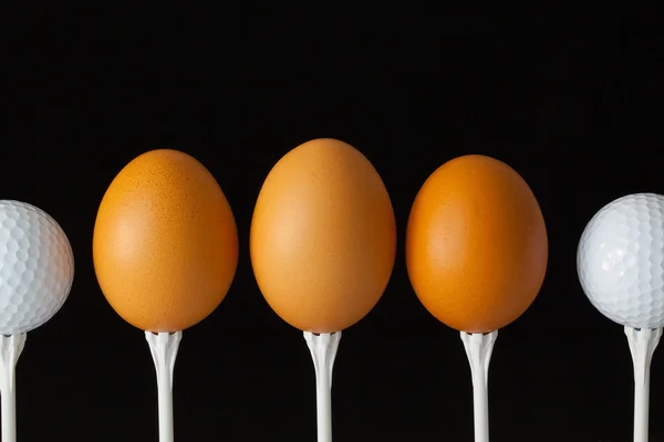 Golf balls and egg on a black glass desk — Stock Photo, Image