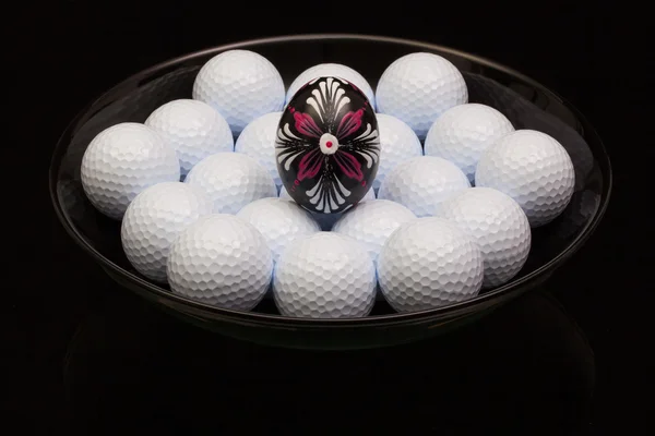 Boules de golf et oeuf sur une assiette noire — Photo