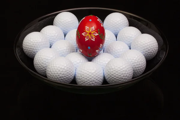 Мячи для гольфа и яйцо на черной тарелке — стоковое фото