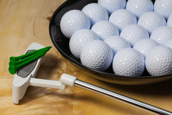 Cuenco de cerámica negro lleno de pelotas de golf y putter — Foto de Stock