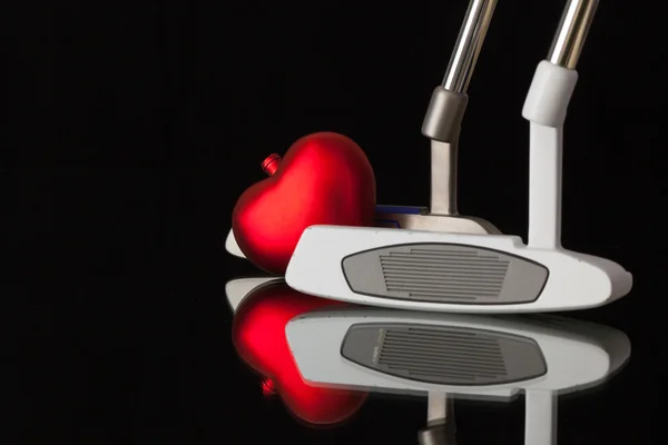 Deux putters de golf différents et coeur rouge — Photo