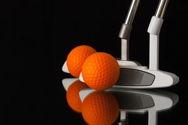 Два разных клюшки для гольфа на черном стеклянном столе — стоковое фото