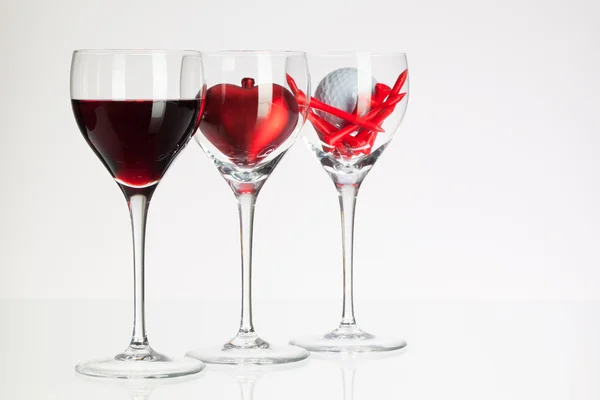 Wine glasses with red wine, heart and golf ball — Stock Photo, Image