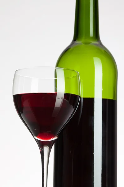 Glas vin och en flaska med rött vin — Stockfoto