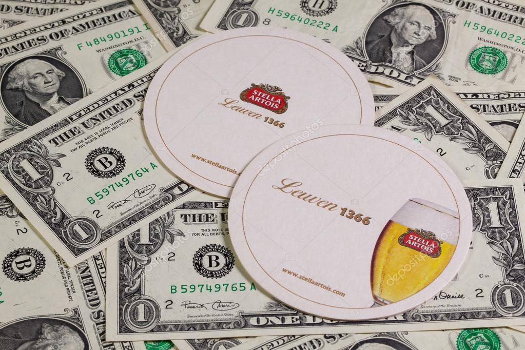 England,London - November 11, 2014:Beermats from Stella Artois and US dollars.It has been brewed in Leuven, Belgium, since 1926.Stella Artois is one of the prominent brands of Anheuser-Busch InBev