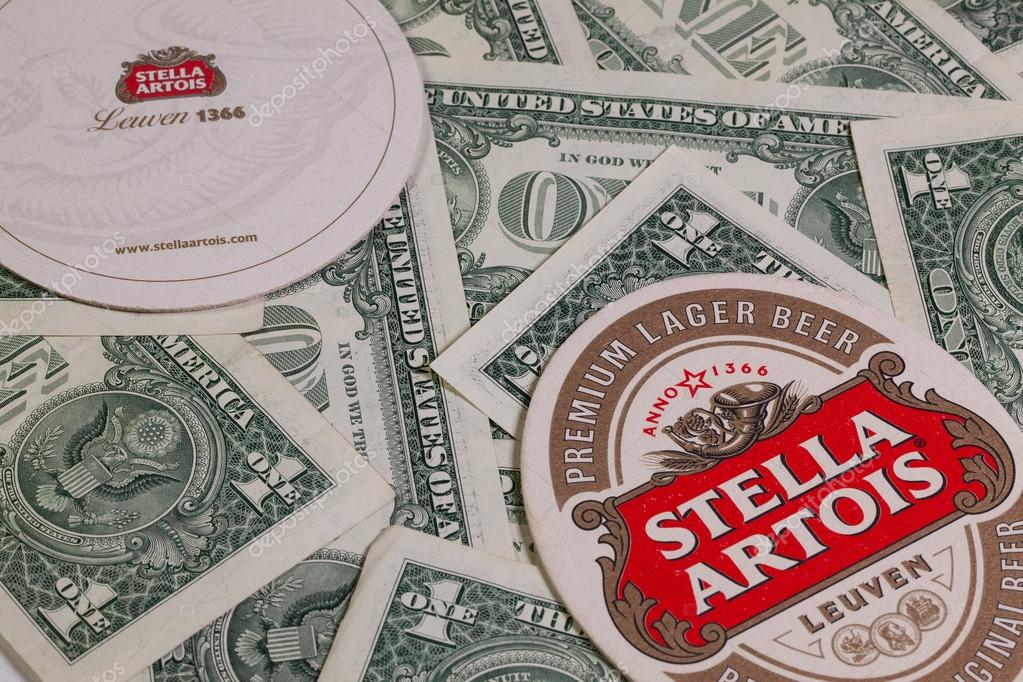 England,London - November 11, 2014:Beermats from Stella Artois and US dollars.It has been brewed in Leuven, Belgium, since 1926.Stella Artois is one of the prominent brands of Anheuser-Busch InBev
