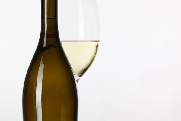 Glass of white wine and brown bottle — Stock Photo, Image