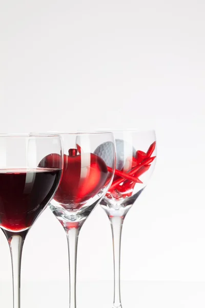 Sklenice na víno s červeným vínem, srdce a golf míček — Stock fotografie