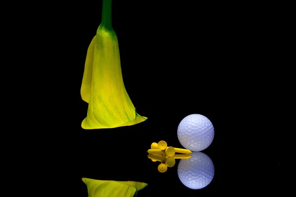 Lirio amarillo calla y pelota de golf en una placa de vidrio negro —  Fotos de Stock