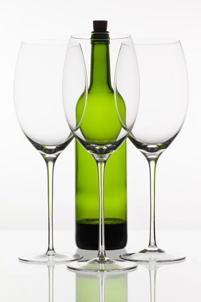 Drie lege glazen wijn en groene fles — Stockfoto