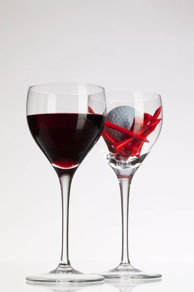 Sklenice na víno s červeným vínem a golf ball — Stock fotografie