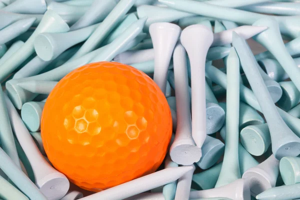 Orangefarbener Golfball liegt zwischen Holzabschlägen — Stockfoto