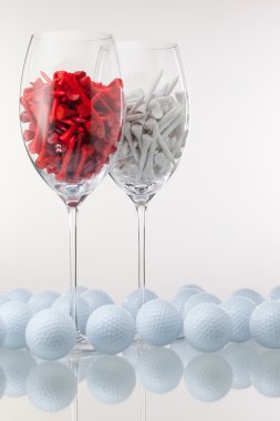 İki kadeh şarap ve golf ekipmanları 