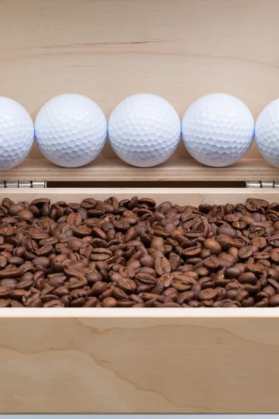 Кофейные бобы и мячи для гольфа в открытой коробке — стоковое фото