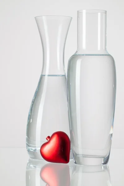 Dois vasos com água limpa e coração vermelho — Fotografia de Stock