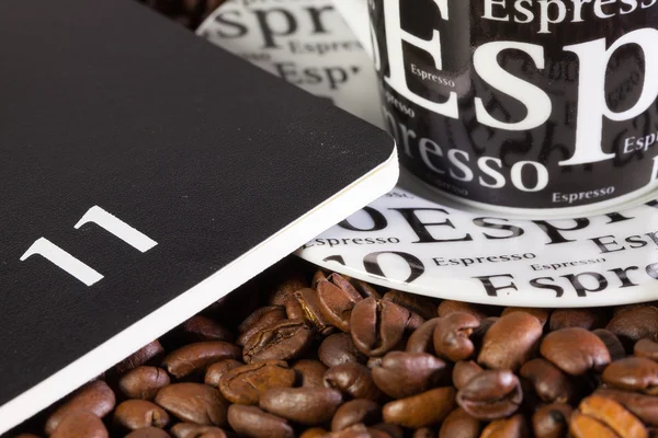 Кофейные зерна, чашка кофе и дневник — стоковое фото