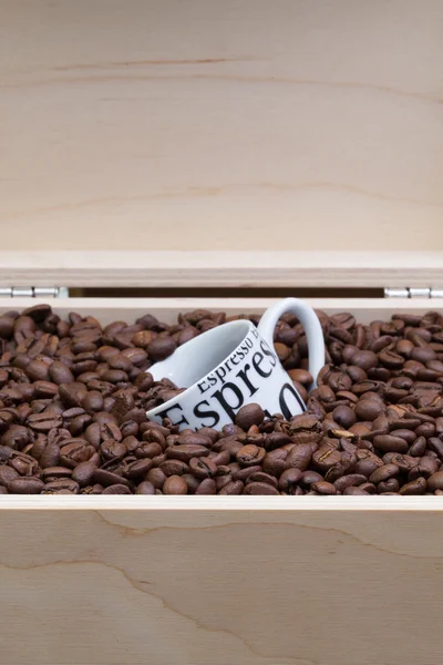 Кофейные зерна и чашка кофе в открытой коробке — стоковое фото
