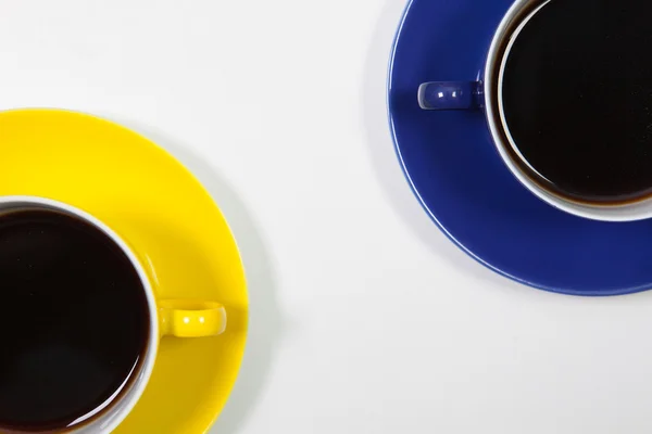 Yellow and blue cups of coffee on a white desk — Stock Photo, Image