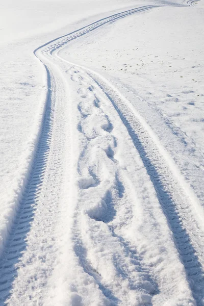 Pneu de voiture piste et empreintes de pas sur la route d'hiver — Photo