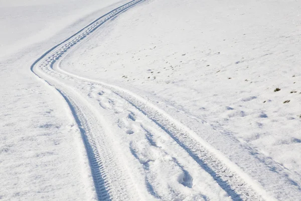 Pneu de carro e pegadas na estrada de inverno — Fotografia de Stock