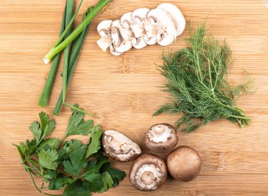 Üst Manzara. Doğranmış mantarlar, yeşil soğanlar, maydanoz ve dereotlu ahşap bir arka planda mesaj için yer var. Boşluğu kopyala.