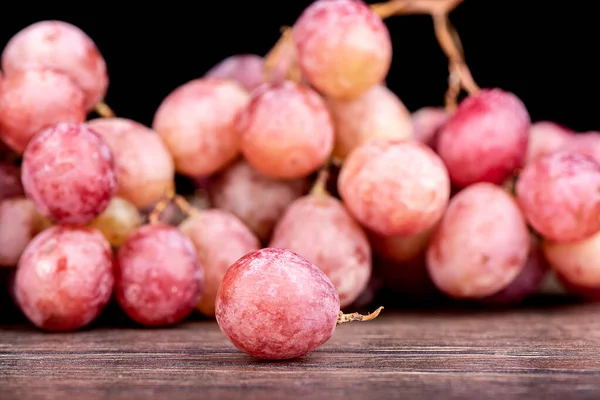 選択的フォーカス ブドウの果実と赤ブドウのぼやけた束 木のテーブルの上のブドウ — ストック写真