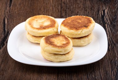 Tahta arka planda beyaz tabakta peynirli krep. Boşluğu kopyala.