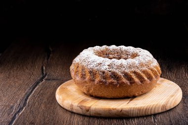 Tahta bir arka planda kesme tahtasındaki yuvarlak kek..