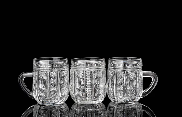 검은 배경에 반사되어 있는 세 개의 빈 수정 컵. — 스톡 사진