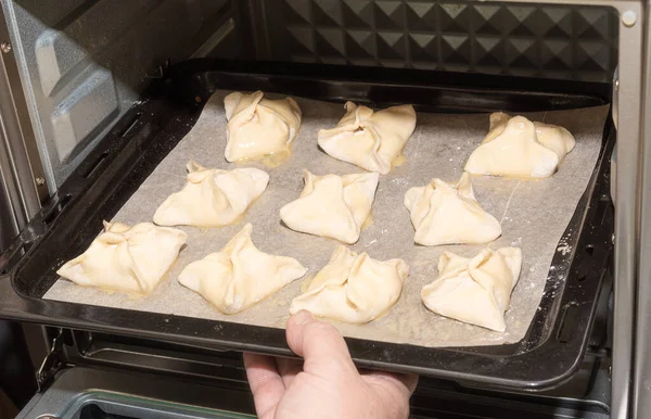 Installing a baking sheet with dessert in the oven.