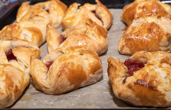 Weicher Fokus. Reihenweise gebackene Dessertumschläge mit Marmelade auf einem Backblech. — Stockfoto