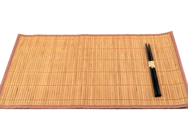 竹子食物垫与黑色筷子隔离在白色背景 传统厨房用具 — 图库照片
