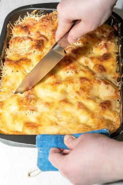 Bıçakla pişirilmiş lazanya dilimlerini kesmek. Evde lazanya yapıyorum..