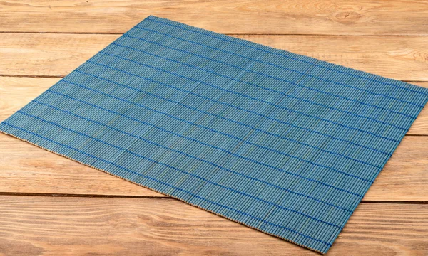 Bamboo blue food mat on wooden background. Close up. Copy space.