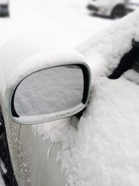 Kar yağdıktan sonra araba aynasında karın yansıması. Kış mevsiminin sorunu. Kapat..