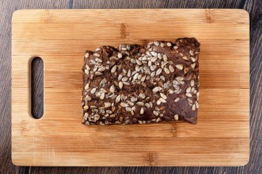 Bir somun çavdar ekmeği ve ayçiçeği çekirdeği. Kesme tahtasındaki ekmek. Üst Manzara. Kapat..