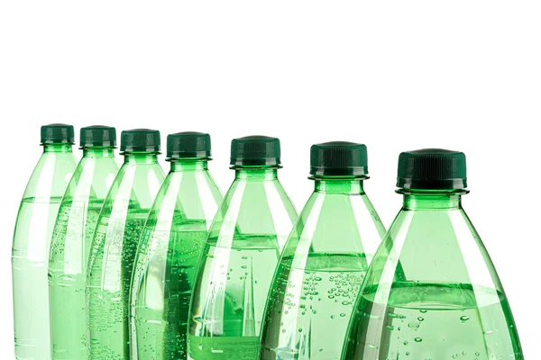 Rad av plastflaskor med mineralvatten på en vit bakgrund. — Stockfoto