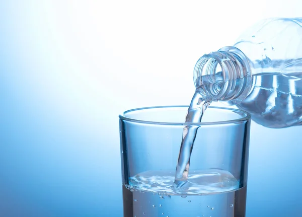 Menuangkan air dari botol plastik ke gelas kimia. — Stok Foto