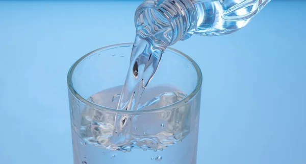Plastik bir şişeden cam bir şişeye doldurulmuş makro su.. — Stok fotoğraf