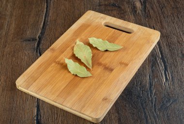 Tahta kesme tahtasında üç kuru yaprak. Boşluğu kopyala.