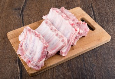 Ahşap bir kesme tahtasının üzerinde sıra sıra çiğ domuz kaburgası. Kapatın. Boşluğu kopyala.