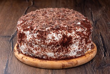 Çikolata parçacıklı kremalı pasta serpiştirilmiş. Tahta kesme tahtasındaki pasta. Ev yapımı kek..